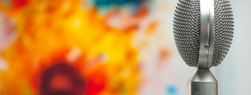 Metal double sided microphone in the foreground with a blurred painting in the background