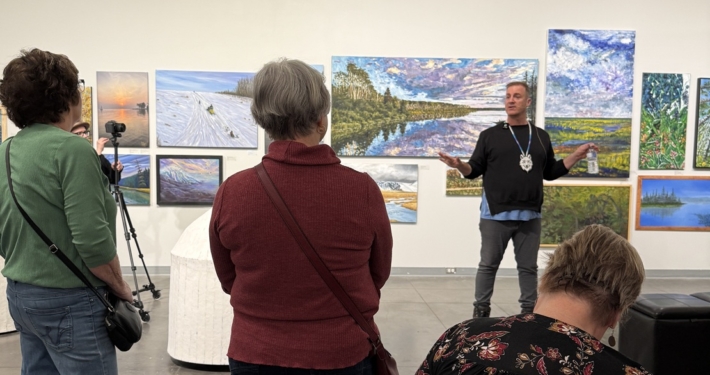 Jason Baerg speaking to a group of visitors during a curatorial talk inside the Mann Art Gallery.