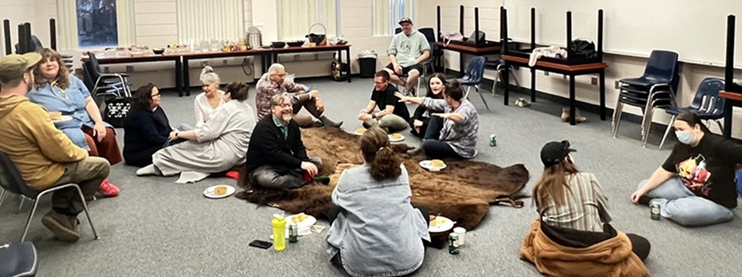 SAA board and staff sitting around buffalo hide with Elder Joseph Naytawhow