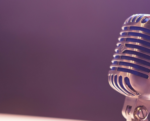 old fashioned metal ball microphone against a flat blue background