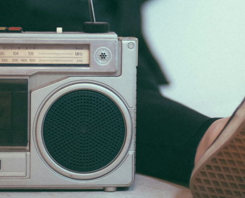 A person laying back with their foot on a Vintage metal stereo. The sole of the other foot is relaxed next to it.
