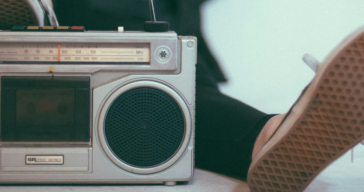 A person laying back with their foot on a Vintage metal stereo. The sole of the other foot is relaxed next to it.