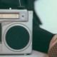 A person laying back with their foot on a Vintage metal stereo. The sole of the other foot is relaxed next to it.