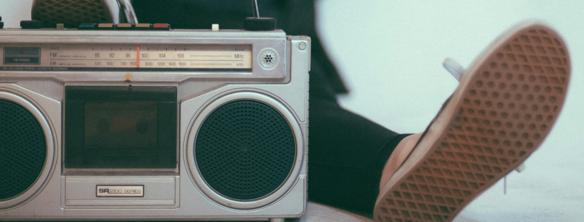 A person laying back with their foot on a Vintage metal stereo. The sole of the other foot is relaxed next to it.