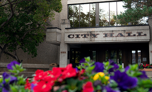 Image of the entrance of Saskatoon's City Hall with colourful flowers in the foreground.