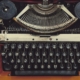 picture of a typewriter, in between a cup of black coffee, a smart phone, and a screenwriting book