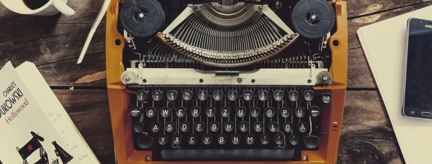picture of a typewriter, in between a cup of black coffee, a smart phone, and a screenwriting book