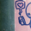 Doodle of person looking at their cellphone with a bubble with a heart at its centre coming from it. The doodle is in blue pen on pink paper.