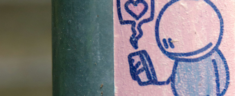 Doodle of person looking at their cellphone with a bubble with a heart at its centre coming from it. The doodle is in blue pen on pink paper.